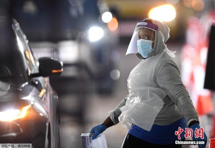 當地時間12月18日，英國政府公布的數據顯示，當天英國新增奧密克戎毒株感染病例10059例。鑒于奧密克戎毒株感染病例激增，住院人數不斷上升，倫敦市長宣布倫敦進入“重大事故”狀態(tài)。圖為倫敦的一個免下車檢測中心，一名醫(yī)務工作者正準備對司機進行核酸檢測。