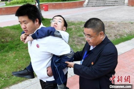 朱金祥背著鐘華強(qiáng)去教室上課的路上，也經(jīng)常碰到值班的校領(lǐng)導(dǎo)和老師前來搭把手。 卓忠偉 攝