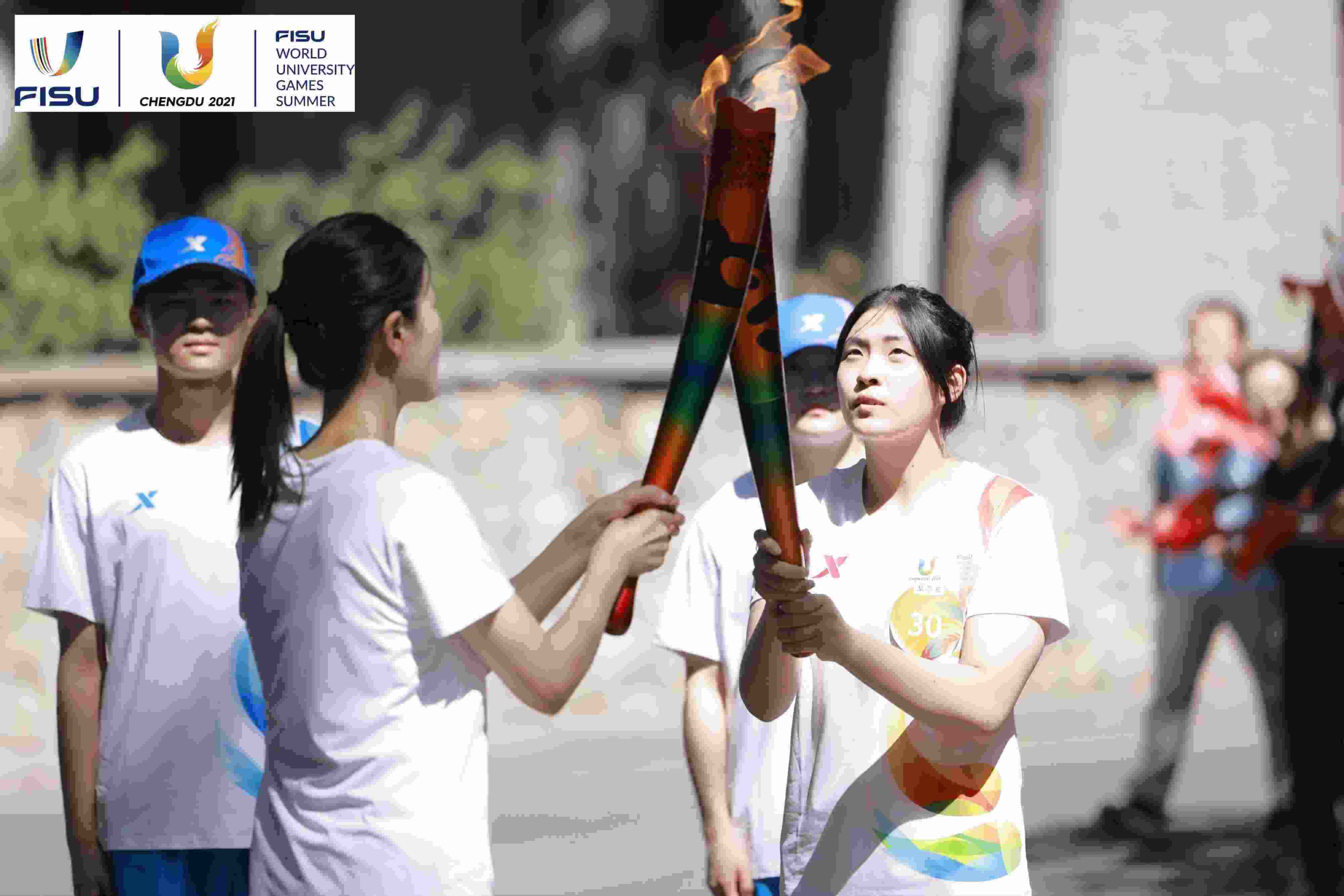 兩名大運(yùn)會(huì)火炬手進(jìn)行火炬?zhèn)鬟f。 圖片來(lái)源：成都大運(yùn)會(huì)執(zhí)委會(huì)供圖