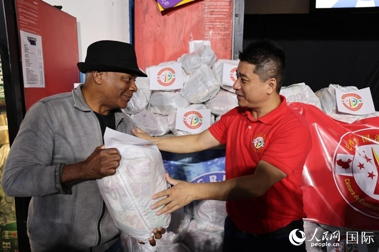 巴西中國浙江商會會長鄭俠茂向社區(qū)居民轉(zhuǎn)交捐贈物資。人民網(wǎng)記者 時元皓攝