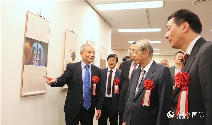 “湖州印象”攝影展主創(chuàng)、世界華人攝影協(xié)會(huì)副會(huì)長(zhǎng)馮學(xué)敏向吳江浩大使、福田康夫前首相等嘉賓介紹展出作品。（人民網(wǎng) 許可攝）