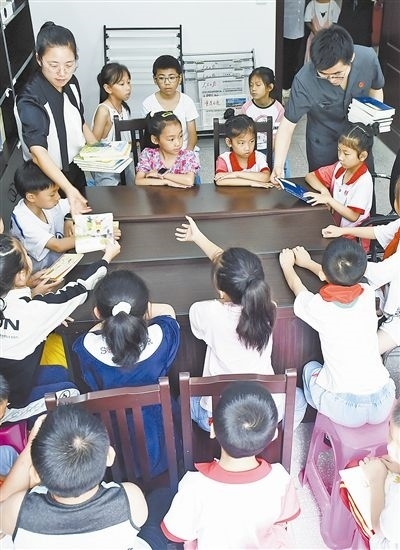  圖④：法院干警為留守兒童發(fā)放暑假讀物。