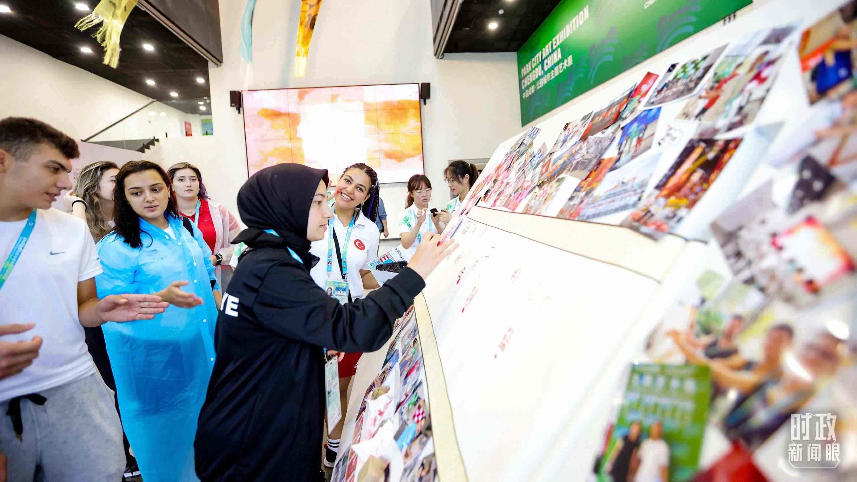各國青年運(yùn)動員正在參觀成都大運(yùn)村內(nèi)的“雪山下的公園城市，煙火里的幸福成都”主題藝術(shù)展。（總臺央視記者魏幫軍拍攝）