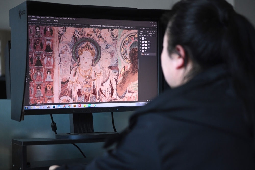 敦煌研究院文物數(shù)字化保護(hù)團(tuán)隊(duì)圖像處理人員年海麗在拼接壁畫圖像（2023年4月25日攝）。數(shù)字化探索為莫高窟的保護(hù)與傳承開辟了全新路徑，數(shù)字技術(shù)讓敦煌文物走出洞窟，跨出國(guó)門，走向“永久保存、永續(xù)利用”。新華社記者 陳斌 攝