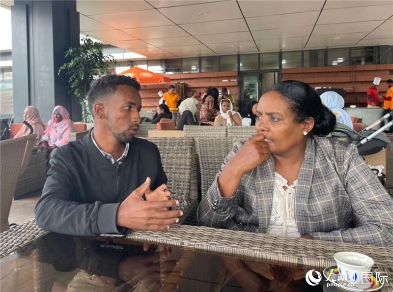 約漢斯（圖左）與德貝拉在友誼廣場(chǎng)咖啡廳交談。人民網(wǎng)記者 趙艷紅攝