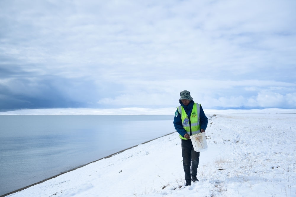2021年10月20日，在青海省果洛藏族自治州瑪多縣扎陵湖鄉(xiāng)勒那村，三江源國(guó)家公園黃河源園區(qū)生態(tài)管護(hù)員在扎陵湖邊撿拾垃圾。新華社記者 張龍 攝