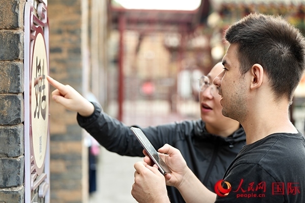 選手安德烈（俄羅斯）在老師指導(dǎo)下學(xué)習(xí)墻壁上張貼的生僻字。人民網(wǎng) 盧鵬宇攝