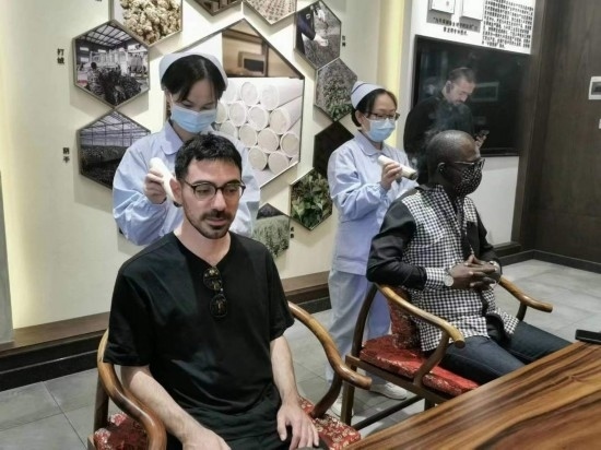 2023“一帶一路”媒體合作論壇聯合采訪團團員在九牛草展示館體驗艾灸。（本報記者 黃超攝）