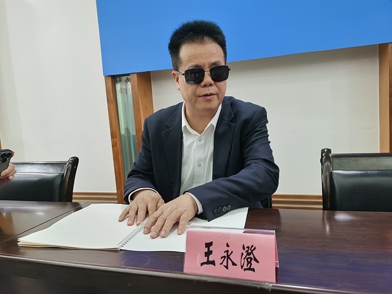 全國(guó)人大代表王永澄正在閱讀盲文版代表建議答復(fù)。本報(bào)記者 張 璁?dāng)z