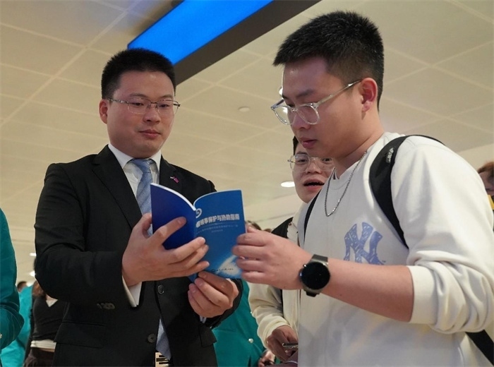 工作人員（左一）在發(fā)放《中國(guó)領(lǐng)事保護(hù)與協(xié)助指南》。 中國(guó)駐迪拜總領(lǐng)事館供圖