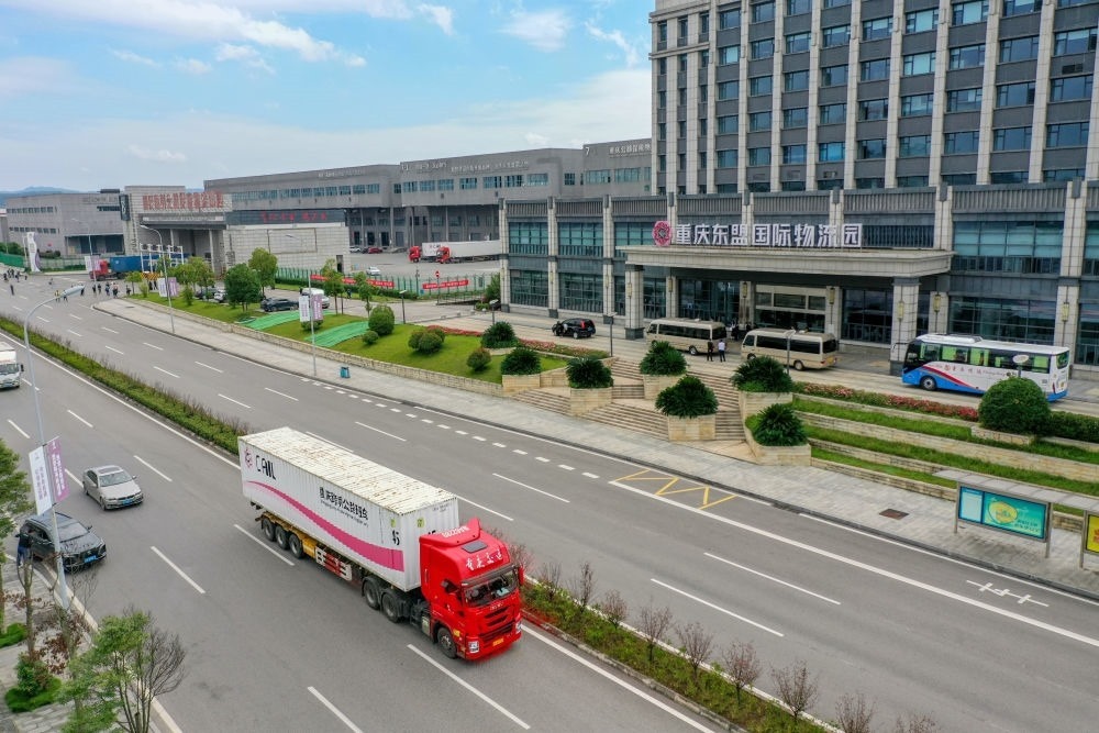 2023年10月11日，滿(mǎn)載筆記本電腦配件、發(fā)電機(jī)組件等產(chǎn)品的西部陸海新通道跨境公路班車(chē)從重慶南彭公路保稅物流中心駛出，將途經(jīng)廣西憑祥，直達(dá)越南（無(wú)人機(jī)照片）。新華社記者 黃偉 攝