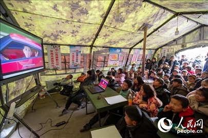 12月22日，在積石山縣大河家鎮(zhèn)大河村安置點(diǎn)，陸軍76集團(tuán)軍某旅搭建的“臨時(shí)學(xué)?！眱?nèi)，小朋友正在看動(dòng)畫片。人民網(wǎng)記者 翁奇羽攝