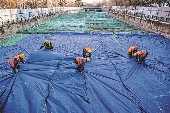 1月3日，房山區(qū)東風(fēng)街道，工人正在修復(fù)的河道內(nèi)給混凝土鋪設(shè)保溫布。