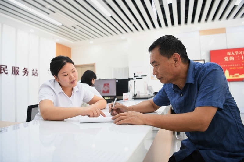 2023年5月23日，河北雄安新區(qū)容東片區(qū)南文營社區(qū)居民（右）在社區(qū)便民服務站辦理業(yè)務。