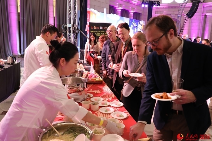 當(dāng)?shù)貢r間3月7日晚，華盛頓聯(lián)合車站廣場舉行駐美使團“使館主廚挑戰(zhàn)賽”。圖為當(dāng)?shù)孛癖娫谥袊古_前體驗中國美食。人民網(wǎng)記者 李志偉攝