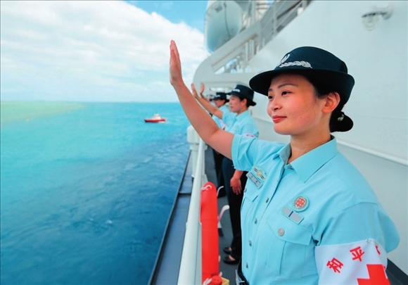 中國(guó)海軍“和平方舟”號(hào)醫(yī)院船結(jié)束訪問(wèn)湯加時(shí)，任務(wù)官兵中的文職人員向歡送人群揮手告別（2023年8月4日攝）。徐巍攝/本刊