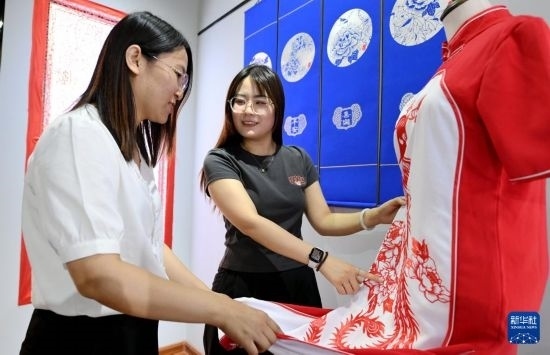 5月31日，在衡水市阜城縣一家剪紙工作室，游客在觀賞帶有剪紙元素的旗袍。