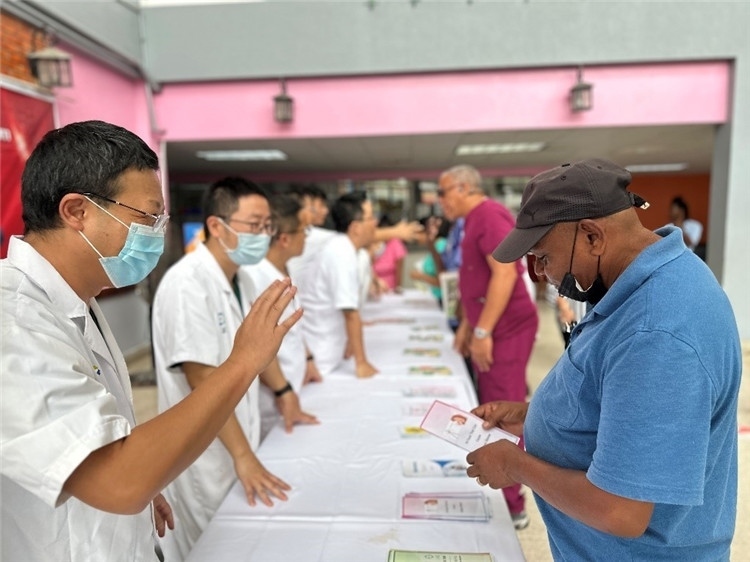 援圭醫(yī)療隊(duì)隊(duì)員們?cè)趩?dòng)儀式上為當(dāng)?shù)孛癖姺职l(fā)宣傳手冊(cè)。中國(guó)援助圭亞那醫(yī)療隊(duì)供圖