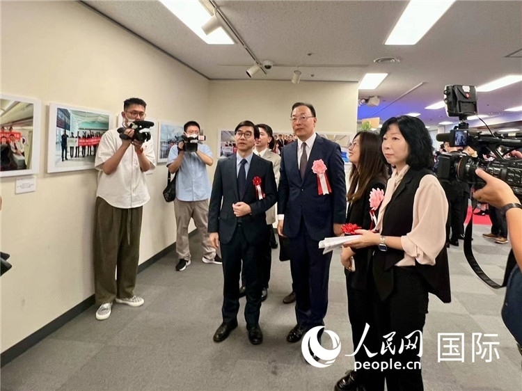 中國國際航空日韓地區(qū)支社支社長馮力為中國駐日本大使館臨時(shí)代辦施泳等嘉賓介紹展出圖片。人民網(wǎng) 許可攝
