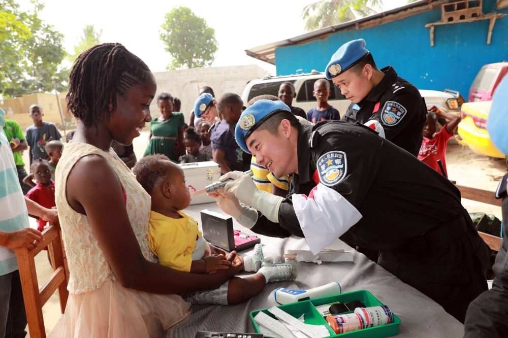 2017年12月28日，在利比里亞蒙羅維亞，中國維和警察防暴隊醫(yī)療人員為兒童做口腔檢查。