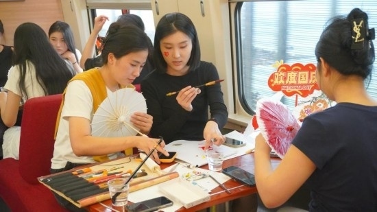 10月1日，旅客們?cè)贕1634次列車上給油紙傘作畫。新華社記者周義 攝