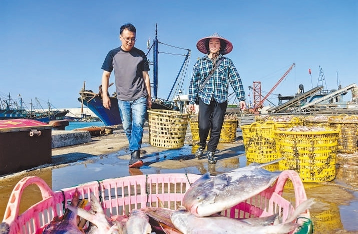 許小斌（左）和漁民一起搬運(yùn)海鮮。本報(bào)記者 付 文攝