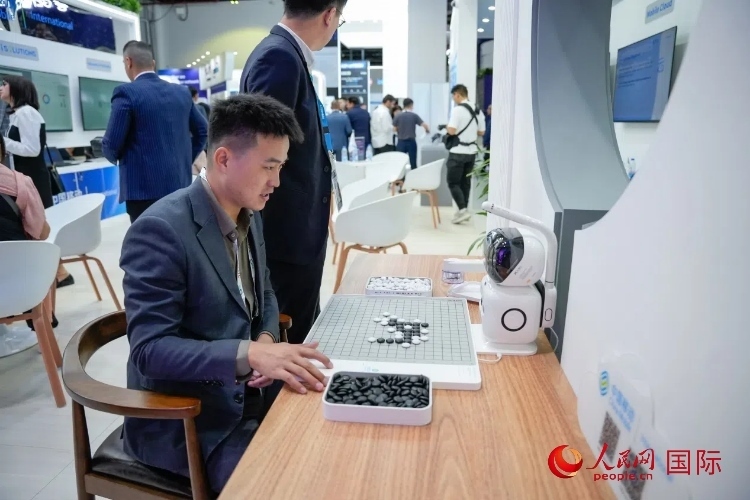 觀眾在中國移動(dòng)國際有限公司展臺(tái)體驗(yàn)智慧圍棋機(jī)器人。人民網(wǎng) 塔里克·易卜拉欣攝