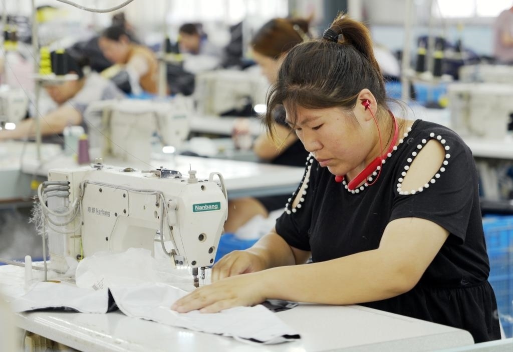 5月20日，村民在李寨村服裝加工廠內(nèi)忙碌。河南省周口市沈丘縣馮營鎮(zhèn)李寨村地處豫東平原。近年來，乘著脫貧攻堅與鄉(xiāng)村振興政策的東風(fēng)，李寨村積極探索產(chǎn)業(yè)發(fā)展模式，通過“龍頭企業(yè)+村集體經(jīng)濟(jì)+農(nóng)戶”的方式，逐漸發(fā)展形成肉牛養(yǎng)殖、設(shè)施農(nóng)業(yè)、服裝加工、康養(yǎng)民宿等產(chǎn)業(yè)，以產(chǎn)業(yè)振興助力鄉(xiāng)村振興。新華社記者 李嘉南 攝