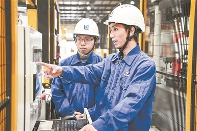 在廣西柳工機械股份有限公司生產(chǎn)車間內(nèi)，一名高級技師（右）給徒弟講解數(shù)控設(shè)備操作細節(jié)。新華社記者 曹祎銘攝