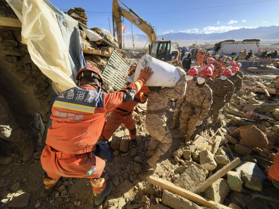 1月11日，定日縣長所鄉(xiāng)古榮村，應(yīng)急消防等救援人員排隊接力搶運掩埋在倒塌房屋下的群眾財物。人民日報記者楊翹楚攝