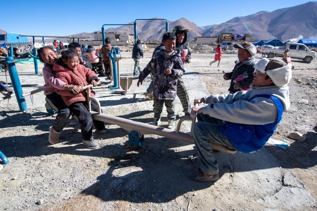 1月11日，在定日縣措果鄉(xiāng)塘仁村安置點，西藏星光社會工作服務(wù)中心志愿者和孩子們一起玩耍，進行災(zāi)后心理疏導。人民網(wǎng)記者 翁奇羽攝