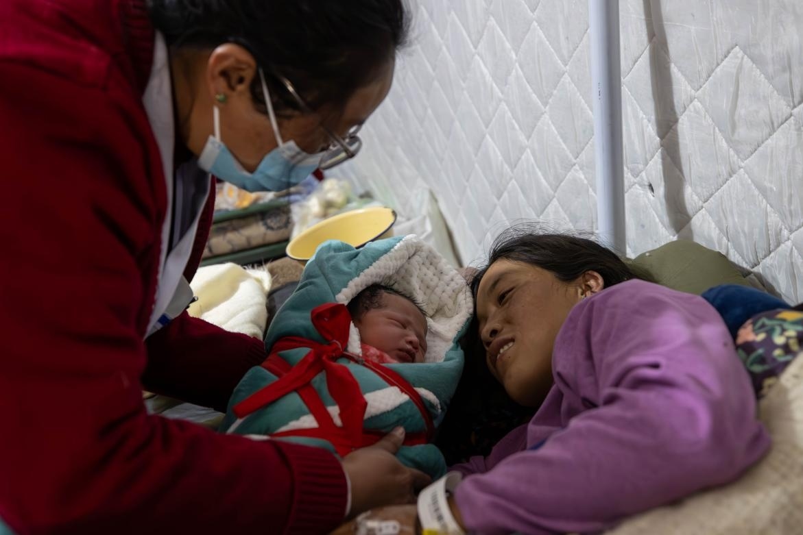 1月10日，定日縣中心醫(yī)院的婦產(chǎn)科醫(yī)生悉心照看一位母親和她懷里的新生兒。人民日報記者張武軍攝