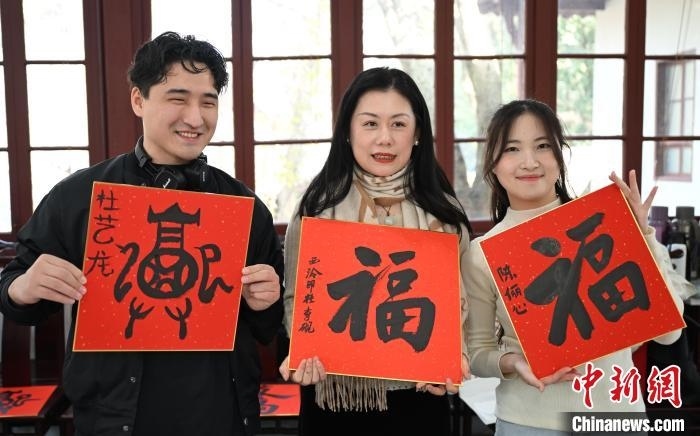 1月20日，外籍留學(xué)生和西泠印社社員李硯(中)展示各自創(chuàng)作的福貼。當(dāng)日，來自巴西、馬來西亞、加納、哈薩克斯坦的外籍留學(xué)生在浙江杭州西泠印社體驗福貼、春聯(lián)和篆刻，感受古老的中國傳統(tǒng)文化。中新社記者 王剛 攝