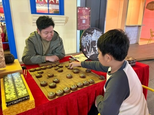 柯秋楓與市民下椰雕象棋。人民網(wǎng) 陳葉欣攝