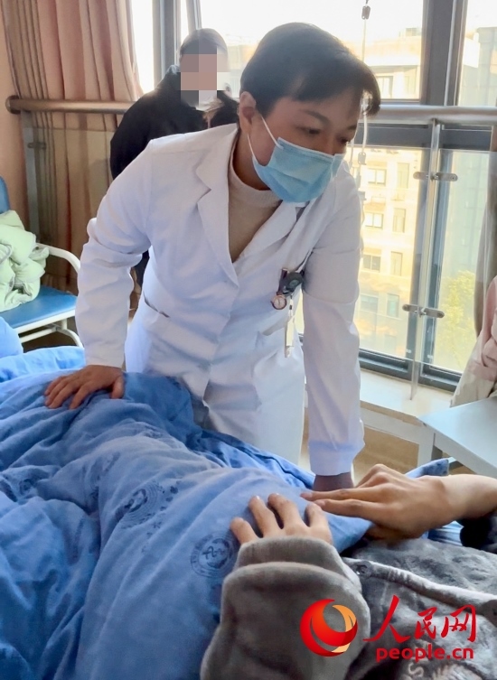 鄧茜查房時(shí)詢問患者情況。人民網(wǎng)記者 金慧慧攝