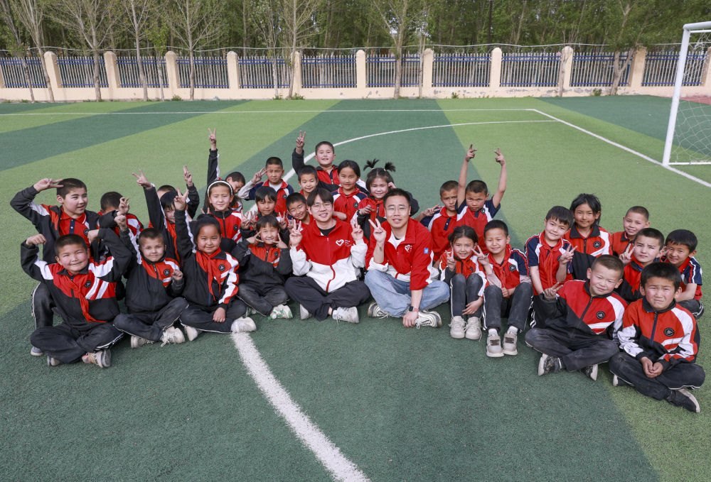 4月23日，在新疆克州阿圖什市哈拉峻鄉(xiāng)謝依特小學(xué)，支教教師王俊文（中左）、李軻凡（中右）和學(xué)生在一起。
